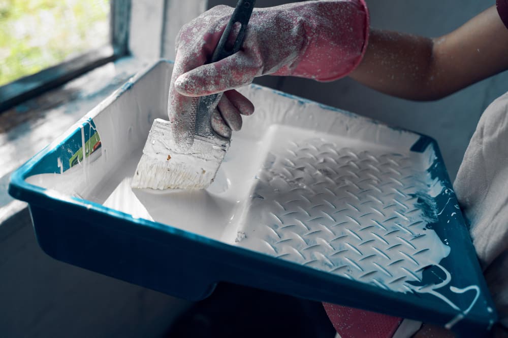 Painter rolling white paint on an interior wall.