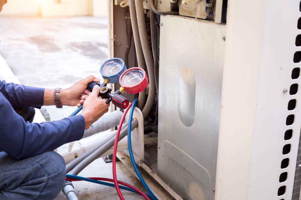 Technician servicing a wall-mounted AC unit in Dubai.