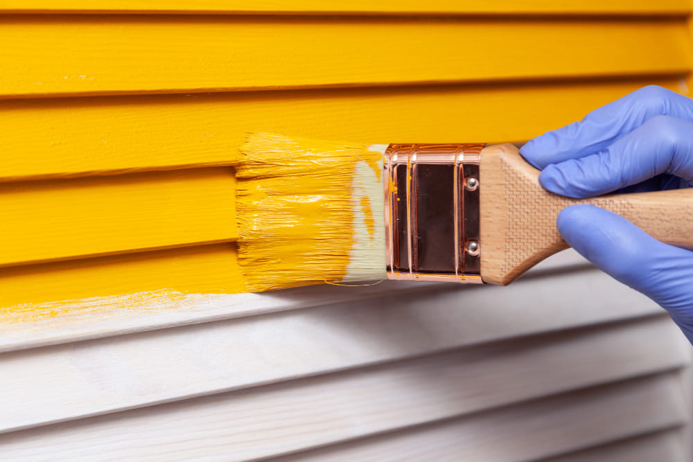 Painter rolling white paint on an interior wall.