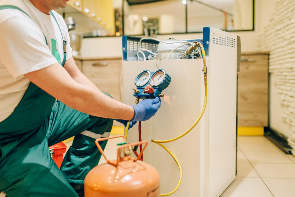 Professional fixing a double-door fridge in a Dubai apartment.