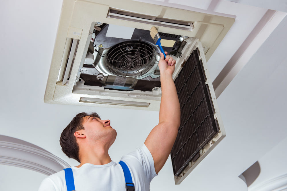 Technician servicing a wall-mounted AC unit in Dubai.