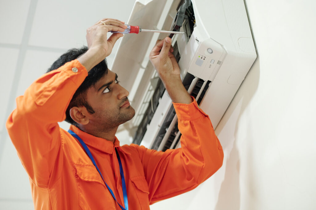 Technician servicing a wall-mounted AC unit in Dubai.