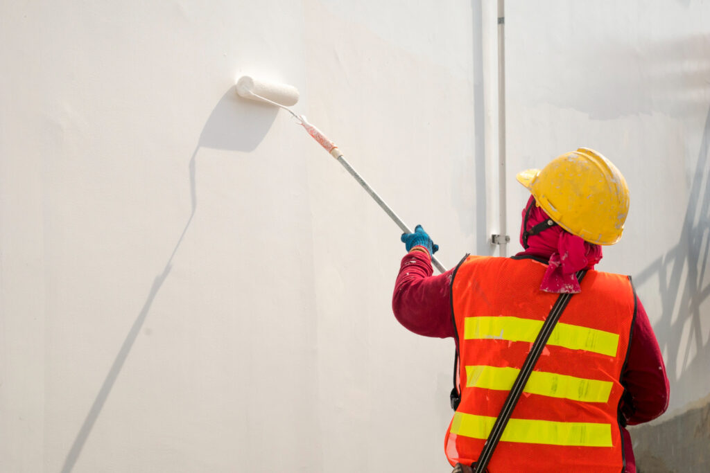 Painter rolling white paint on an interior wall.