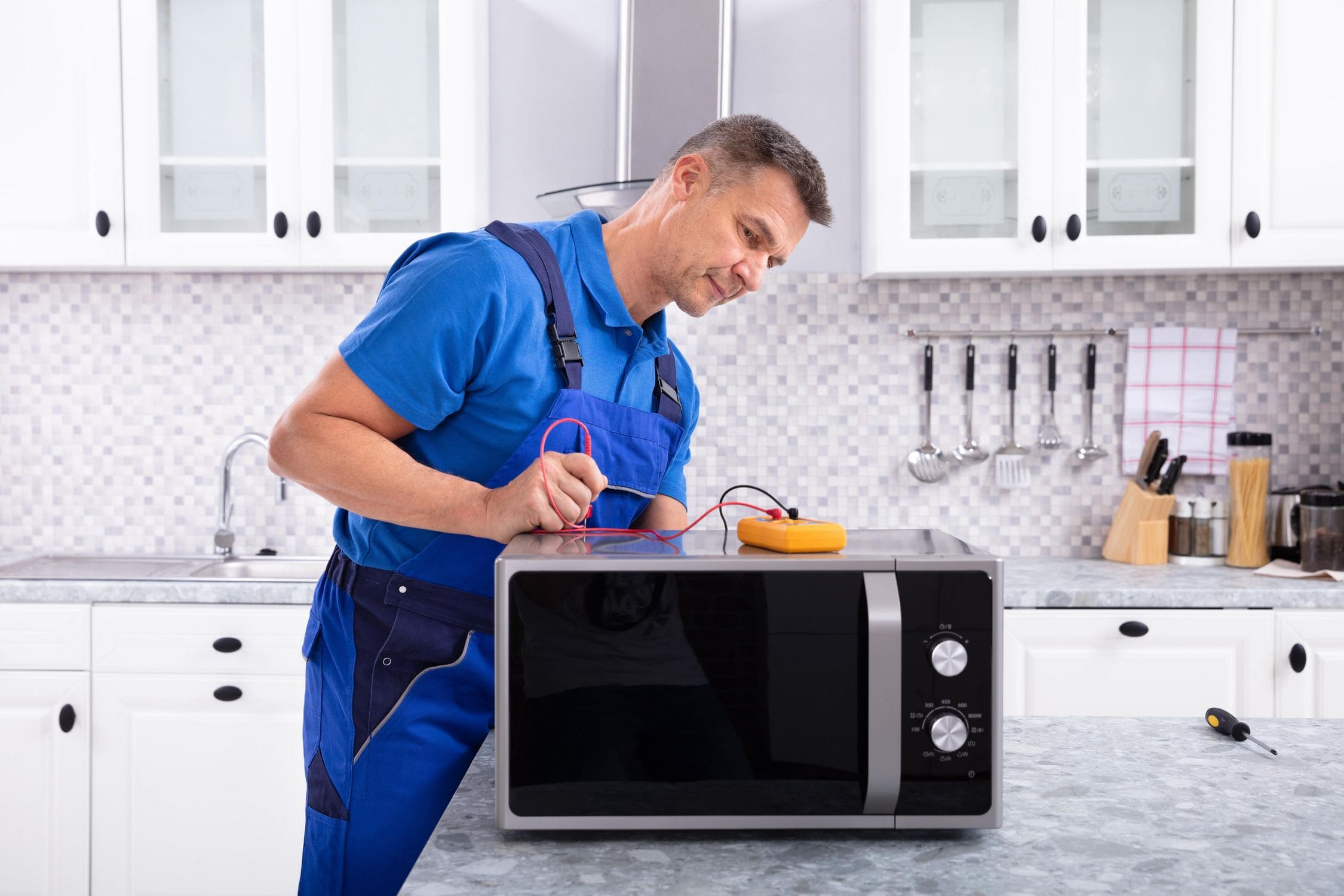 Technician opening a countertop microwave for inspection.